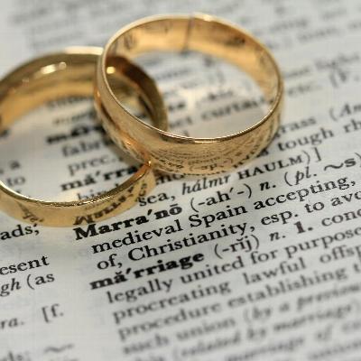 two wedding rings sitting on one another on a dictionary defining marriage